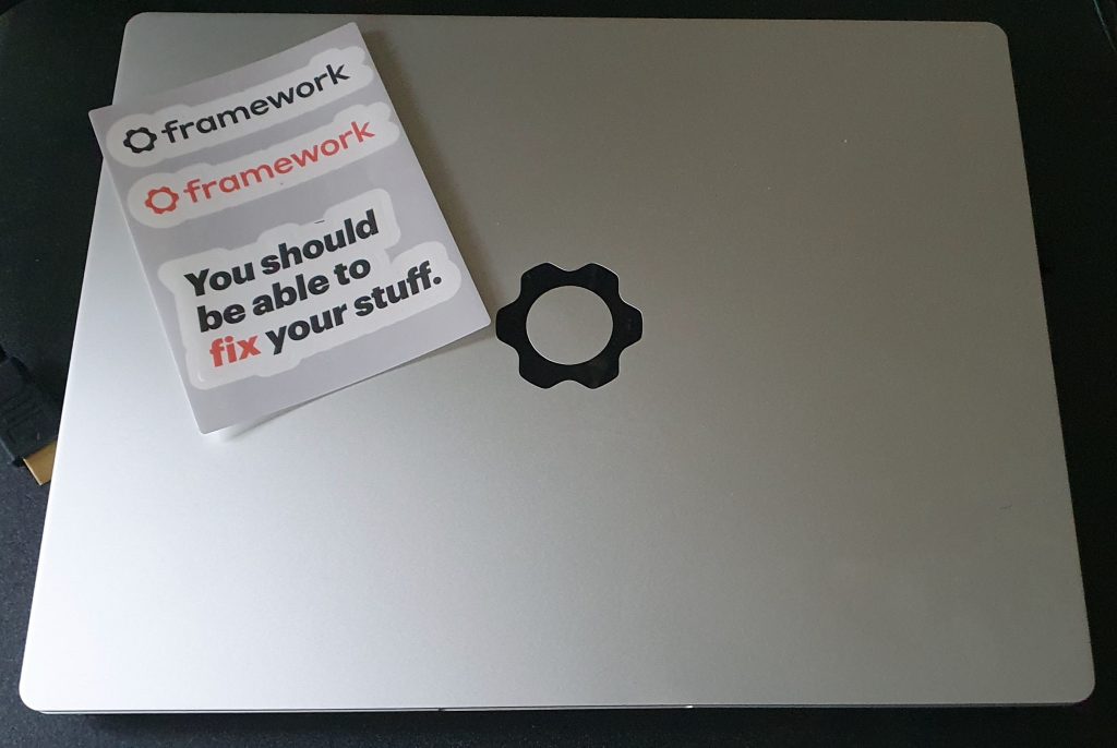 歯車のロゴがついたシルバーカラーの13インチノートパソコンの上に、framework書かれたブランドステッカーと、"You should be able to fix your stuff"(自分のものは自分で修理できるべき)というスローガンのステッカーが載せてある。